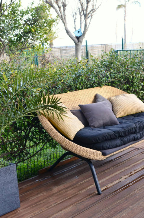 Coin cozy avec un canapé en fibres tressées et des coussins